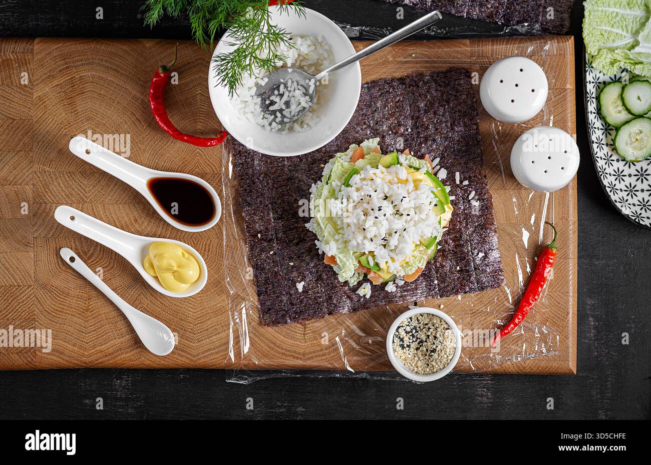 Il processo di creazione di un creativo sushi hamburger con salmone, uova fritte, formaggio, cetrioli e avocado su uno sfondo testurizzato. Fase 8. Vista dall'alto Foto Stock