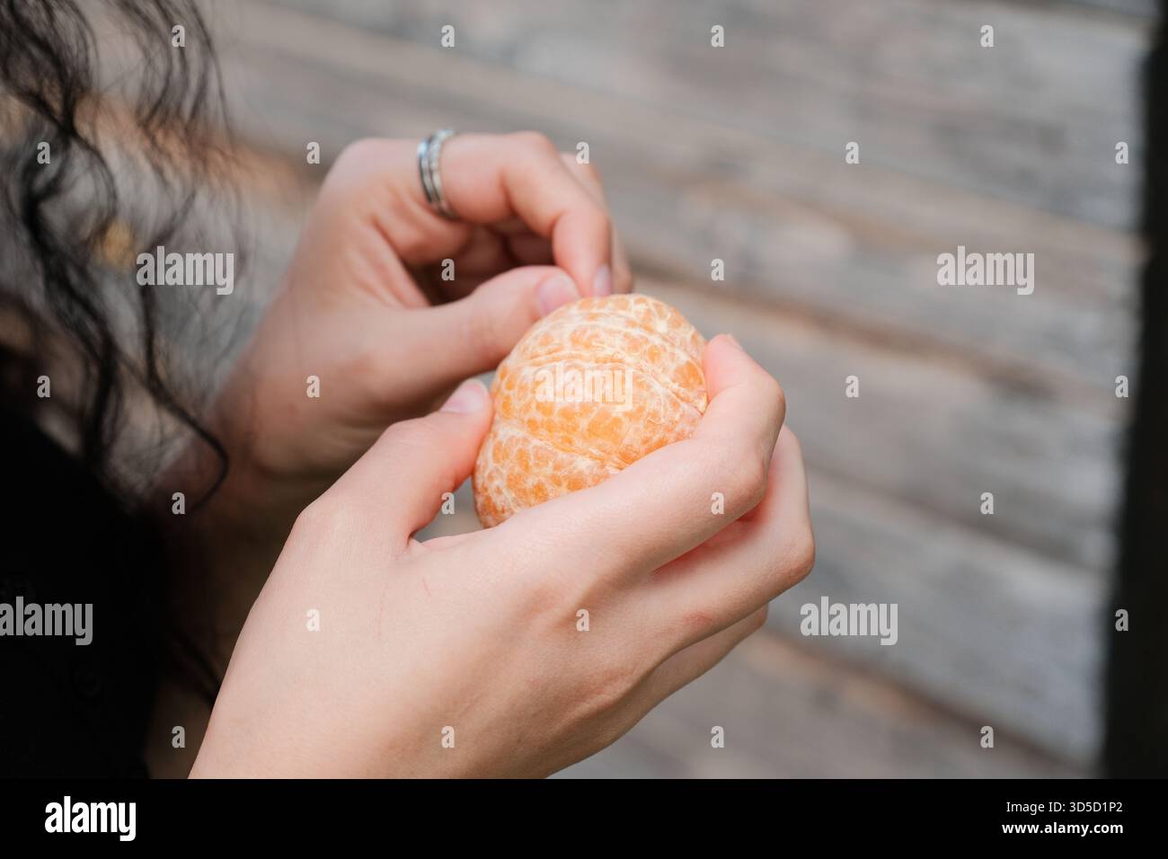Mani che sbucciano un fresco mandarino all'aperto Foto Stock