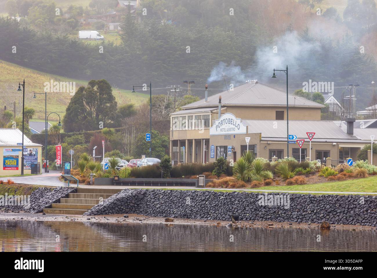 Portobello, un villaggio sulla penisola di Otago, nuova Zelanda. Il fumo sorge dal camino dello storico Portobello Hotel Foto Stock
