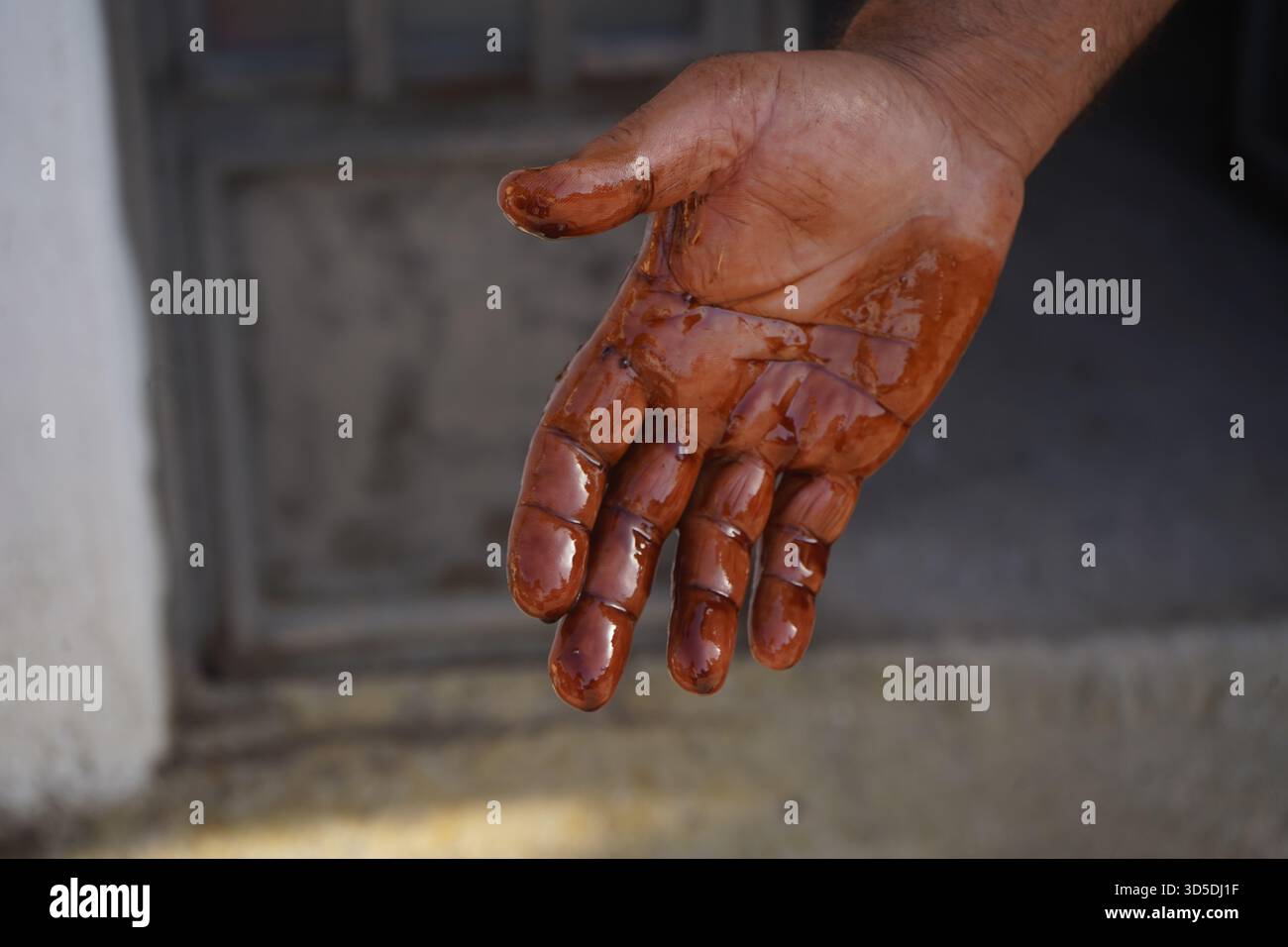 Primo piano estremo della mano allungata di un uomo, gocciolando con olio motore scuro e denso dopo un'attività di manutenzione automobilistica. Foto Stock