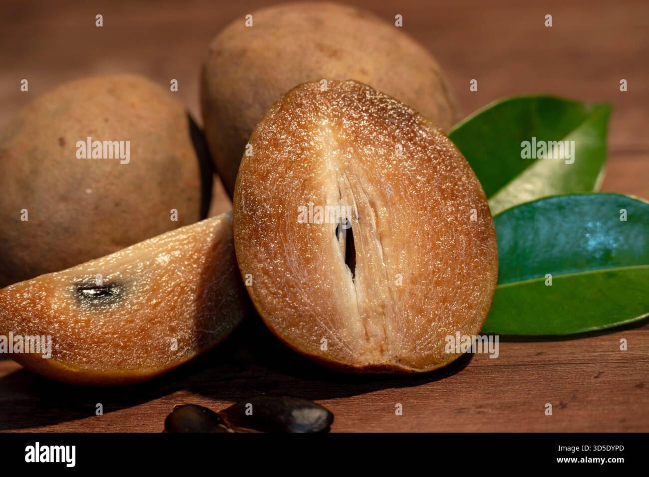 Sapodilla fresca biologica senza sostanze chimiche (Manilkara zapota) dolce e gustosa frutta con foglia verde su fondo in legno Foto Stock