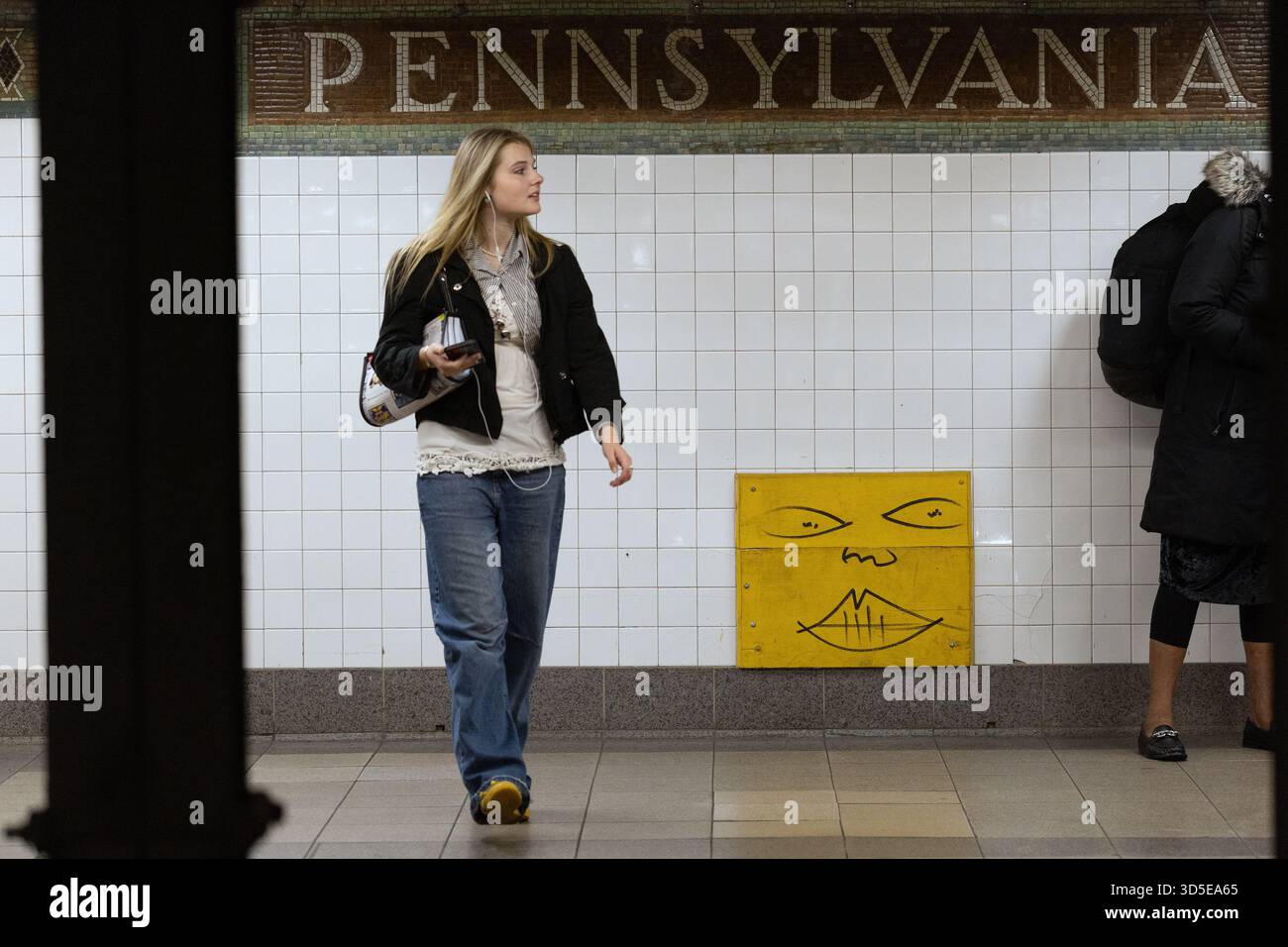 Giovane donna che aspetta sul binario della metropolitana di Penn Station a New York City Foto Stock
