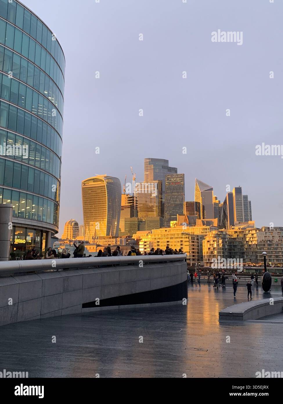 Skyline del quartiere finanziario di Canary Wharf con moderni grattacieli che si riflettono sul marciapiede bagnato lungo il fiume Tamigi. Il panorama degli affari urbani - Immagine stock catturata con smartphone