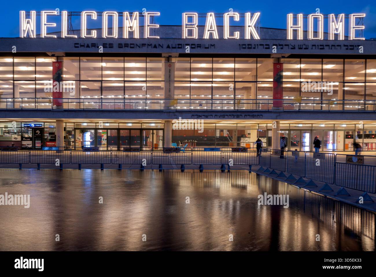 Tel Aviv, Israele. 15 novembre 2025. Civili israeliani visti davanti al Charles Bronfman Auditorium, che si trova accanto al Mann Auditorium, in Piazza Habima a Tel Aviv, Israele, mentre il grande cartello "Welcome Back Home" si illumina al tramonto di sabato 15 novembre 2025. Israele attende gli ultimi tre cadaveri che gli Hamas dovrebbero tornare per completare la prima fase del piano di pace sostenuto dagli Stati Uniti tra Israele e le forze di Hamas. La fase 2, quando avrà inizio, sarà cruciale, in quanto Hamas dovrebbe disarmarsi. Foto di Jim Hollander/UPI credito: UPI/Alamy Live News Foto Stock