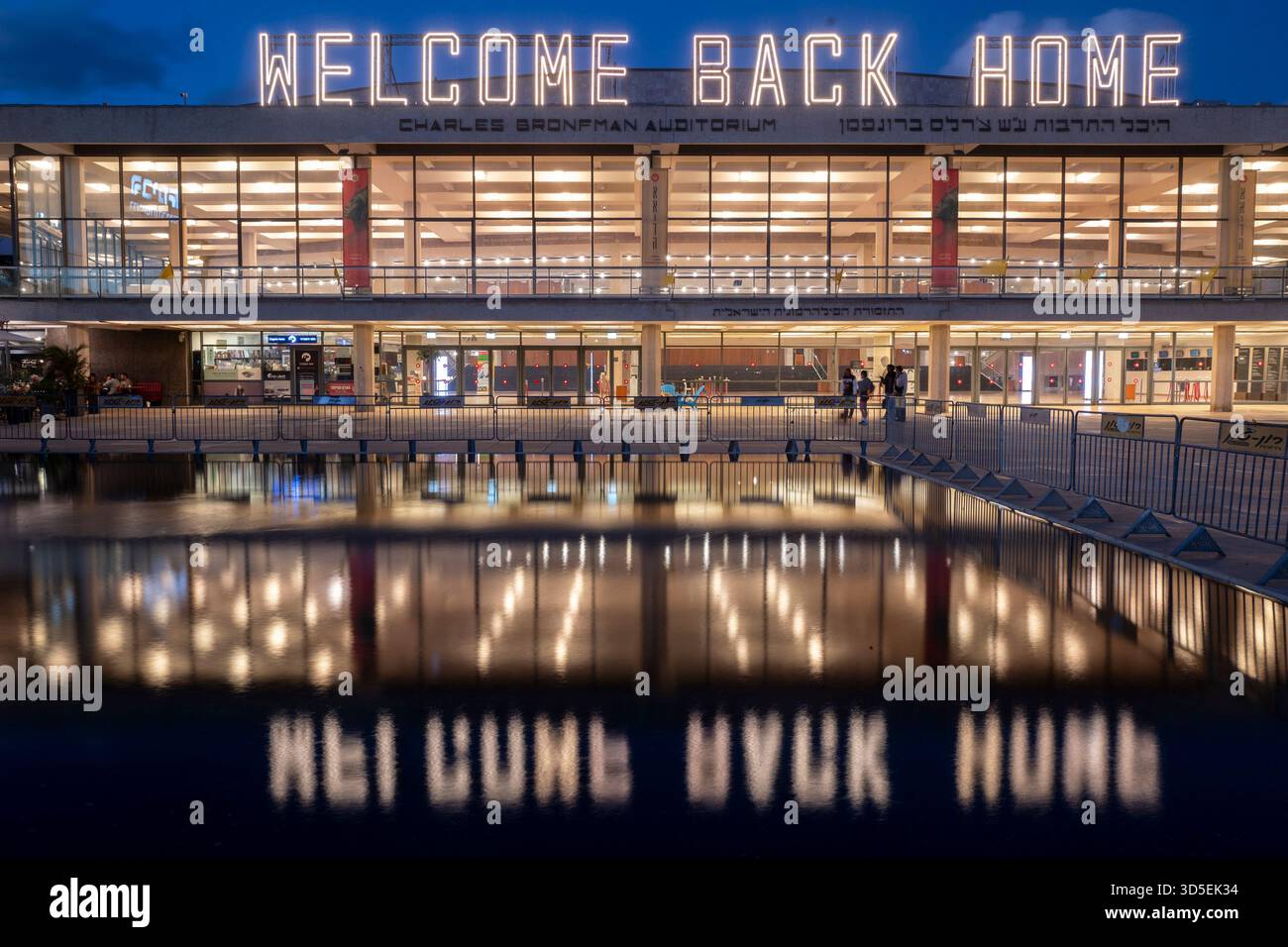 Tel Aviv, Israele. 15 novembre 2025. Civili israeliani visti davanti al Charles Bronfman Auditorium, che si trova accanto al Mann Auditorium, in Piazza Habima a Tel Aviv, Israele, mentre il grande cartello "Welcome Back Home" si illumina al tramonto di sabato 15 novembre 2025. Israele attende gli ultimi tre cadaveri che gli Hamas dovrebbero tornare per completare la prima fase del piano di pace sostenuto dagli Stati Uniti tra Israele e le forze di Hamas. La fase 2, quando avrà inizio, sarà cruciale, in quanto Hamas dovrebbe disarmarsi. Foto di Jim Hollander/UPI credito: UPI/Alamy Live News Foto Stock