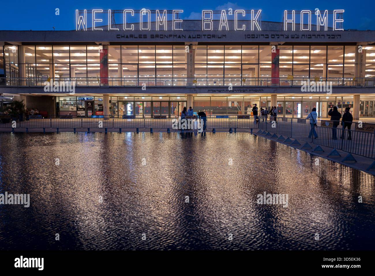Tel Aviv, Israele. 15 novembre 2025. Civili israeliani visti davanti al Charles Bronfman Auditorium, che si trova accanto al Mann Auditorium, in Piazza Habima a Tel Aviv, Israele, mentre il grande cartello "Welcome Back Home" si illumina al tramonto di sabato 15 novembre 2025. Israele attende gli ultimi tre cadaveri che gli Hamas dovrebbero tornare per completare la prima fase del piano di pace sostenuto dagli Stati Uniti tra Israele e le forze di Hamas. La fase 2, quando avrà inizio, sarà cruciale, in quanto Hamas dovrebbe disarmarsi. Foto di Jim Hollander/UPI credito: UPI/Alamy Live News Foto Stock