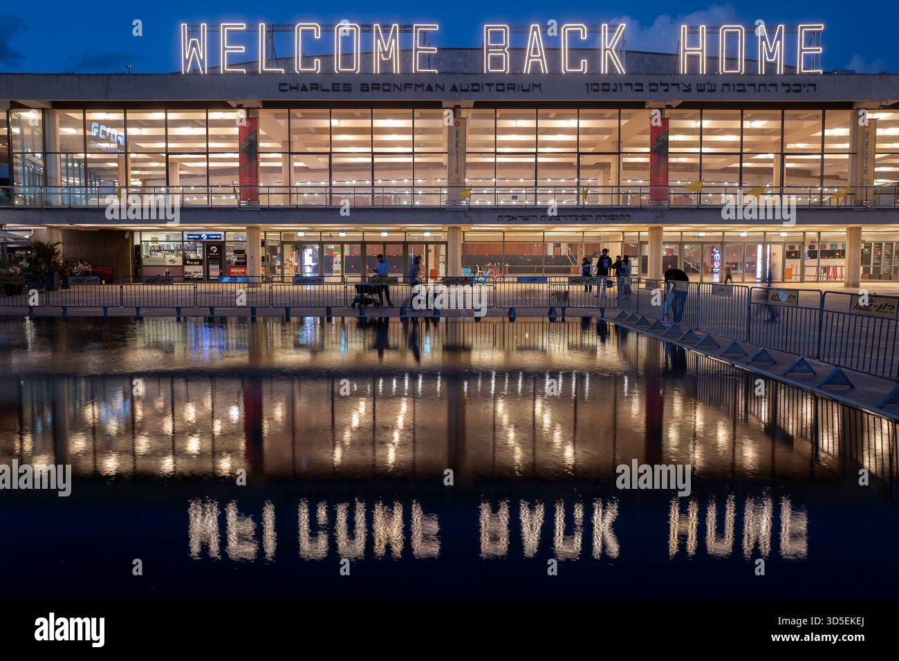 Tel Aviv, Israele. 15 novembre 2025. Civili israeliani visti davanti al Charles Bronfman Auditorium, che si trova accanto al Mann Auditorium, in Piazza Habima a Tel Aviv, Israele, mentre il grande cartello "Welcome Back Home" si illumina al tramonto di sabato 15 novembre 2025. Israele attende gli ultimi tre cadaveri che gli Hamas dovrebbero tornare per completare la prima fase del piano di pace sostenuto dagli Stati Uniti tra Israele e le forze di Hamas. La fase 2, quando avrà inizio, sarà cruciale, in quanto Hamas dovrebbe disarmarsi. Foto di Jim Hollander/UPI credito: UPI/Alamy Live News Foto Stock