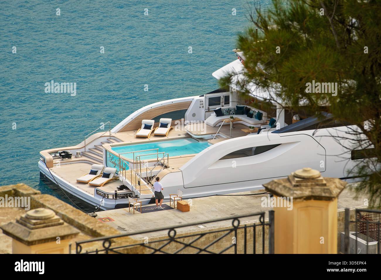 La Valletta, Malta - 11.05.2025: Un moderno yacht bianco di lusso con piscina e lettini da mare in calme acque blu, a creare un'atmosfera rilassante. Foto Stock
