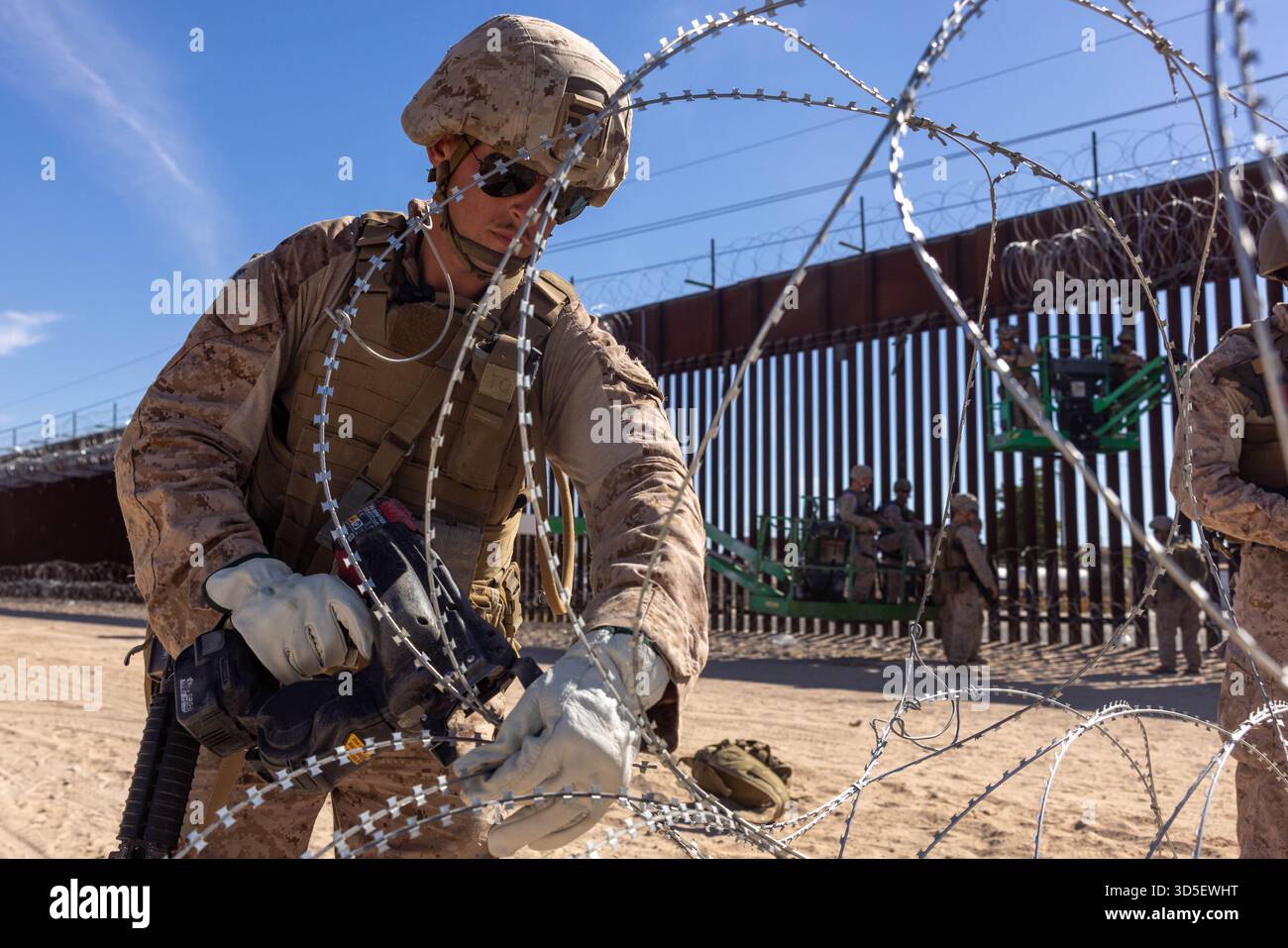 Yuma, Stati Uniti. 31 ottobre 2025. US Marines con Combat Logistics Battalion 15, Combat Logistics Regiment 17, 1st Marine Logistics Group, assegnato al Joint Task Force-Southern Border, srotolare fasci di filo di concertina prima di installarli sul muro di barriera del confine meridionale con il Messico, 31 ottobre 2025 vicino a Yuma, Arizona. Crediti: CPL. Noah Martinez/US Marines Photo/Alamy Live News Foto Stock