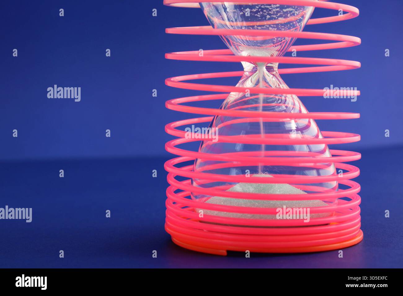 Restrizioni e tempo limitato, clessidra intrappolata all'interno di una spirale circolare Foto Stock