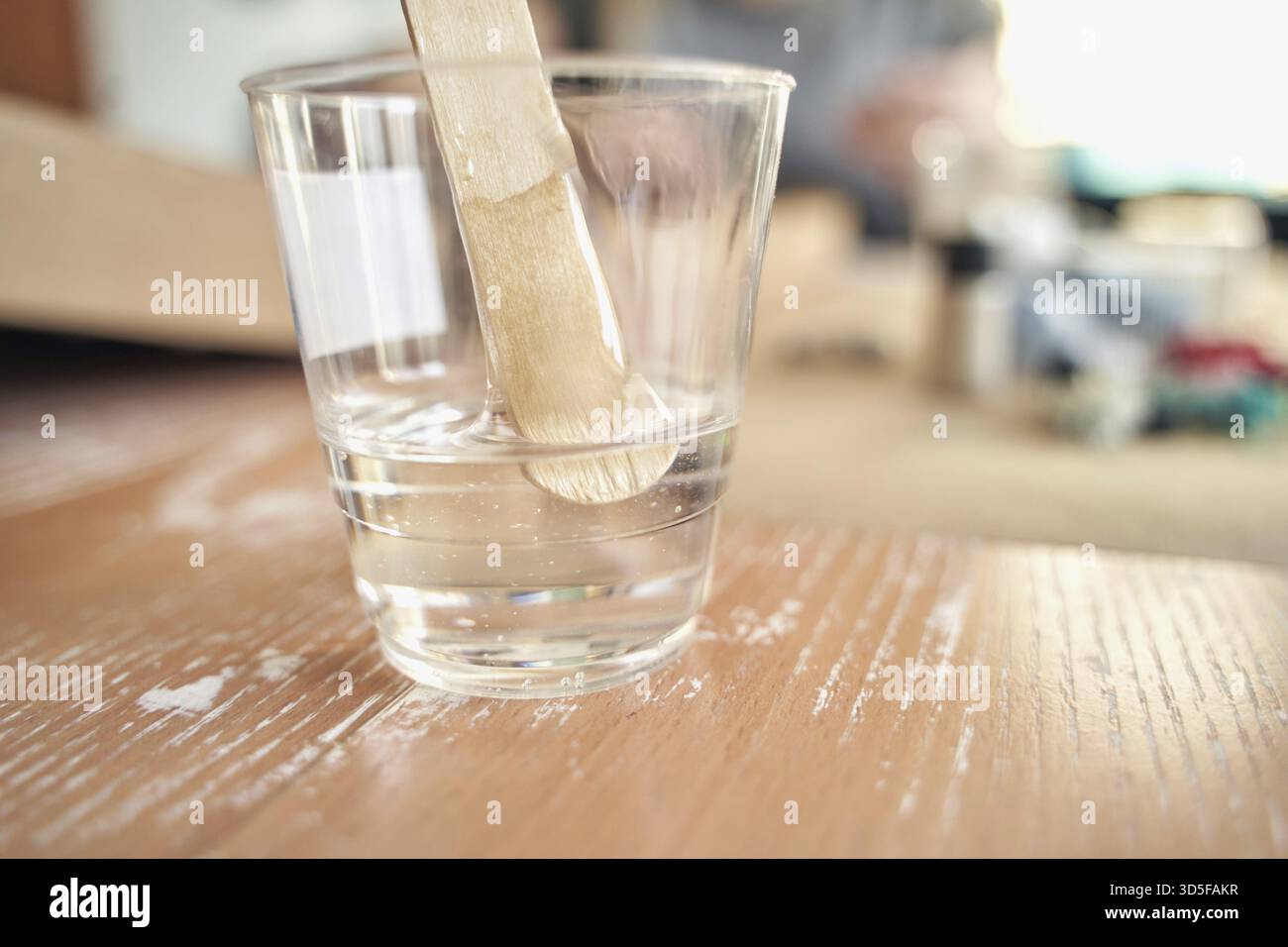 Tazza in plastica trasparente con bastoncino di agitazione su una superficie in legno in un ambiente ben illuminato Foto Stock