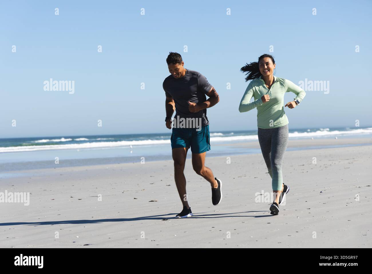 Coppie che fanno jogging sulla spiaggia, si godono gli esercizi mattutini e la fresca brezza dell'oceano, spazio per fotocopie Foto Stock