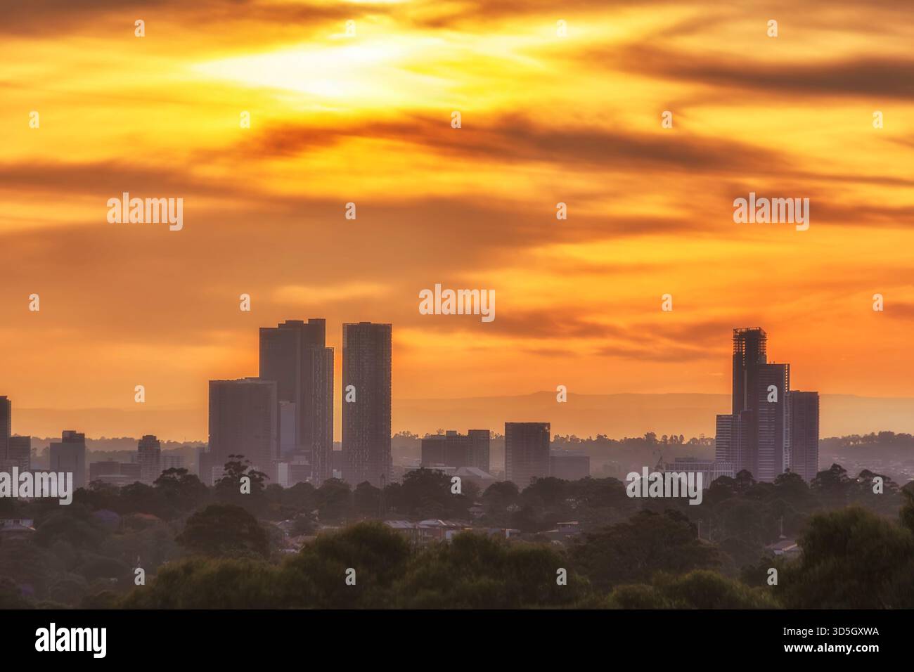 Alte e distanti torri commerciali del CBD di Parramatta al tramonto sullo sfondo del suggestivo cielo arancione in Australia con vista sulla città. Foto Stock