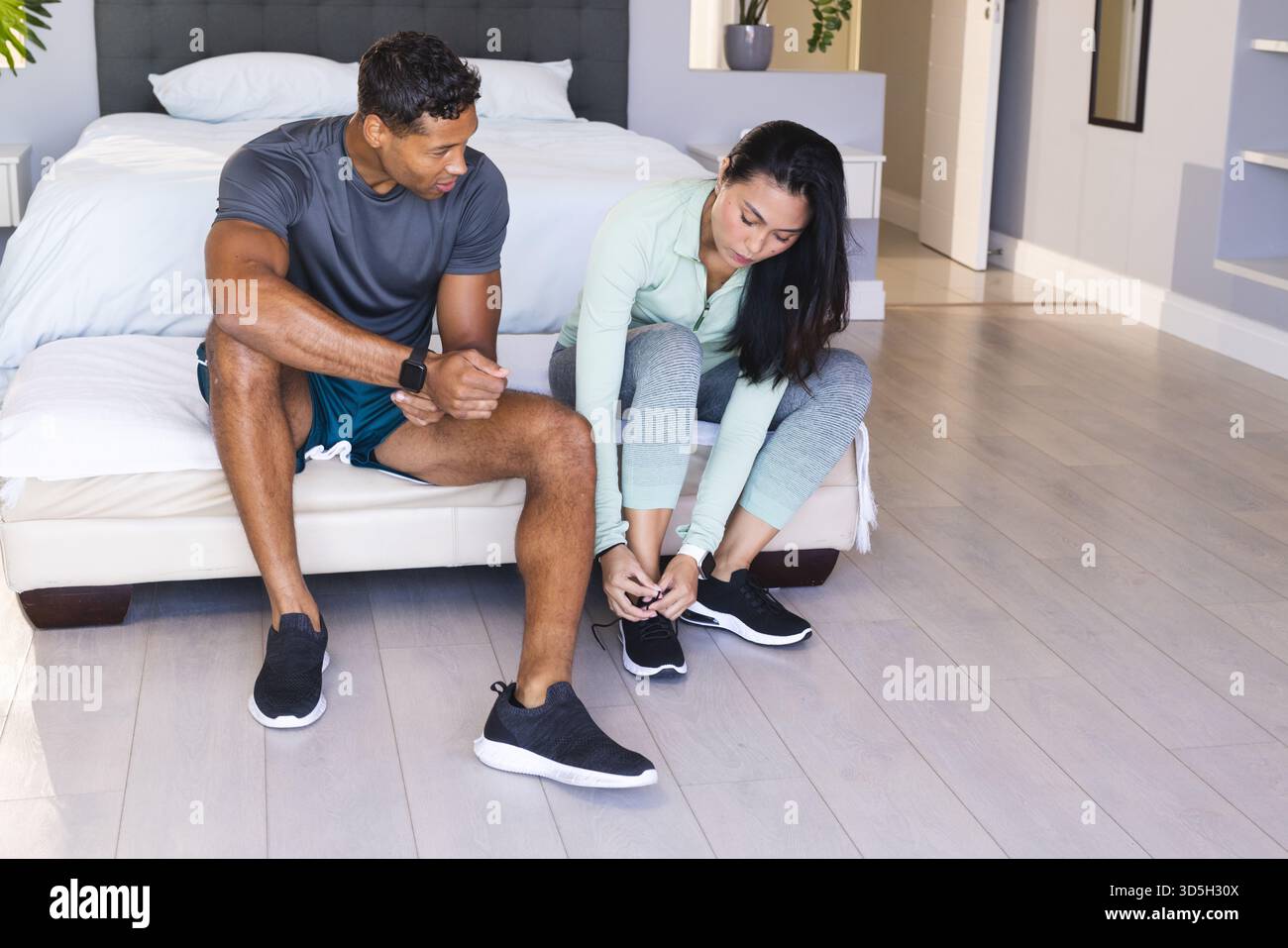 Allacciare le scarpe, la coppia si prepara per l'allenamento mattutino in camera da letto Foto Stock