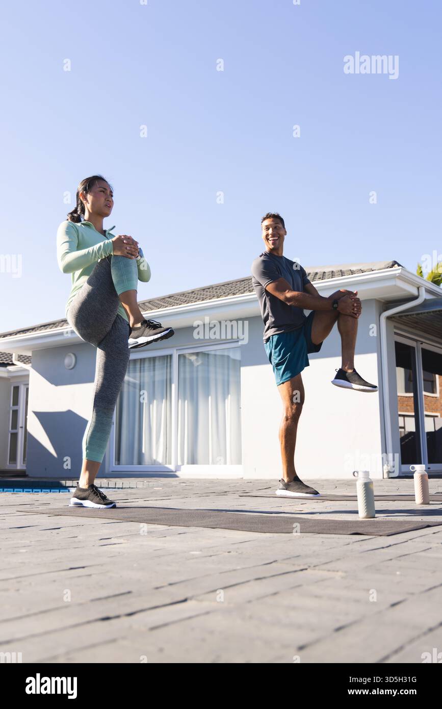 Accoppiatevi per fare esercizio all'aperto, allungando le gambe insieme nelle giornate di sole a bordo piscina Foto Stock