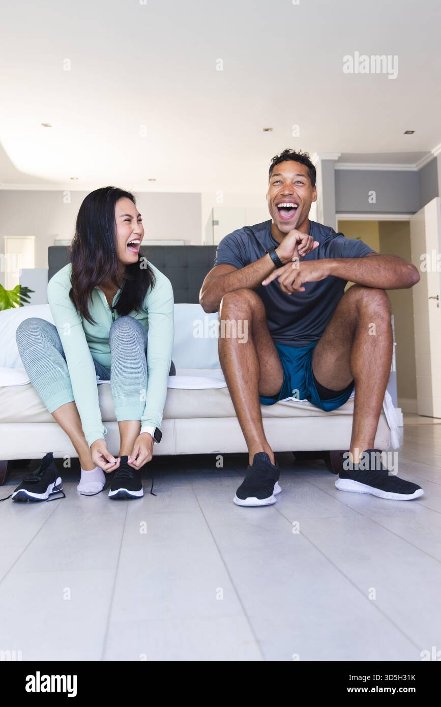 Coppia che ride insieme mentre si prepara per l'allenamento mattutino a casa Foto Stock
