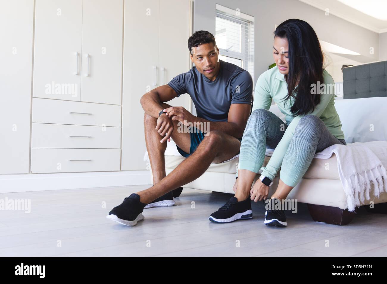 Coppia a casa per prepararsi all'allenamento mattutino, legando lacci alle scarpe da ginnastica Foto Stock