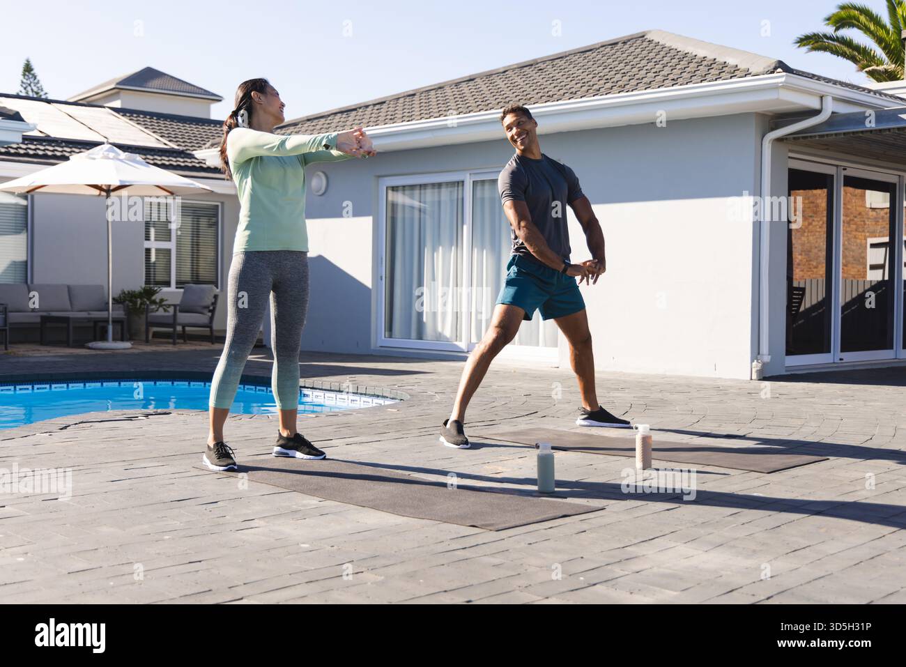 Coppia che si allenano all'aperto vicino alla piscina, si allungano e si allenano insieme Foto Stock
