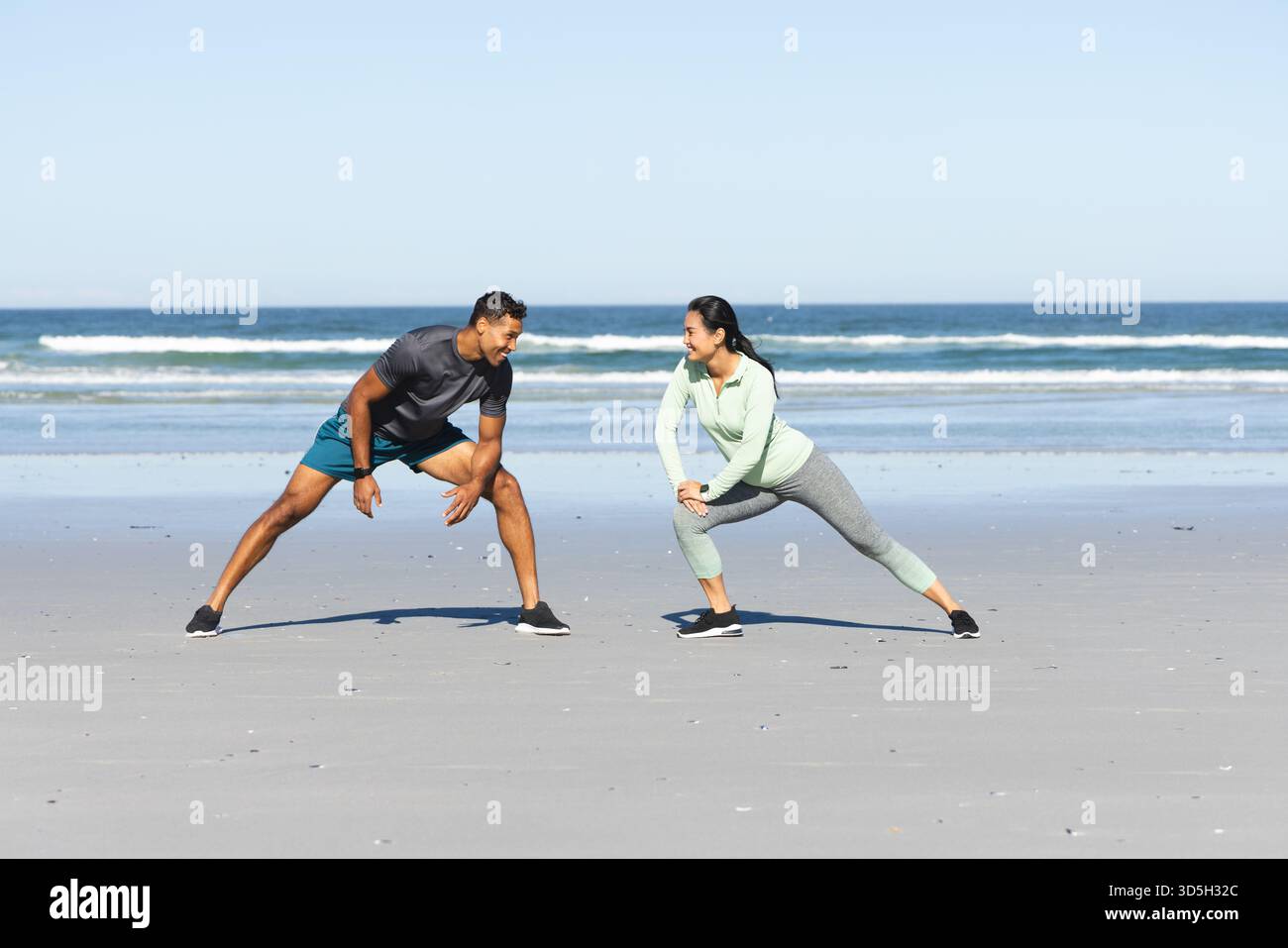 Ci si allunga sulla spiaggia, si fa l'esercizio mattutino sull'oceano insieme Foto Stock