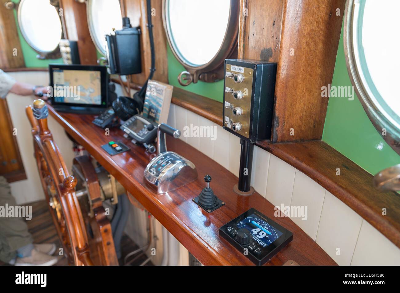 Il ponte del Western Flyer a Rainbow Harbor mostra pannelli di navigazione, comandi dell'acceleratore, ruota della nave e finestre dell'oblò. Credito: Erik Morgan Foto Stock