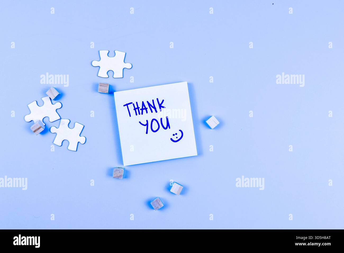 Nota DI RINGRAZIAMENTO con la faccia sorridente, i pezzi del puzzle e i cubi di legno trasformano gratitudine attraverso una disposizione visiva giocosa e creativa. Foto Stock