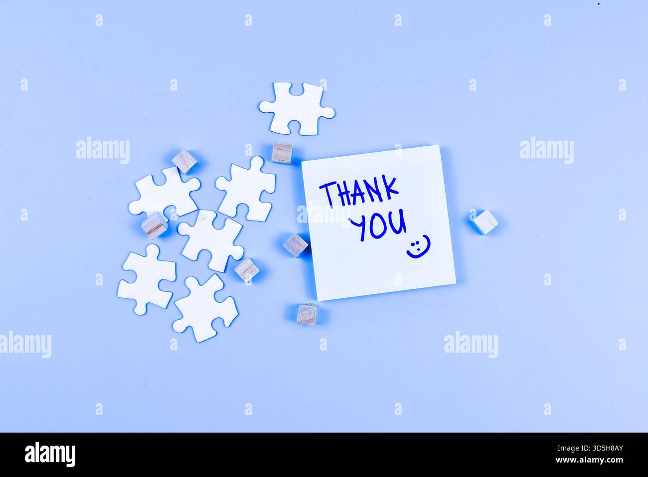 Nota DI RINGRAZIAMENTO con la faccia sorridente, i pezzi del puzzle e i cubi di legno trasformano gratitudine attraverso una disposizione visiva giocosa e creativa. Foto Stock