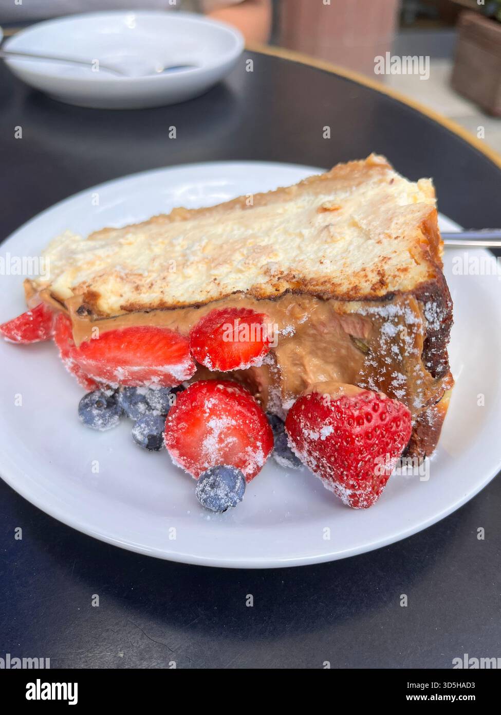Primo piano di pancake serviti con fragole e mirtilli freschi su un piatto bianco in una caffetteria di Varsavia, in Polonia. Colazione accogliente Foto Stock