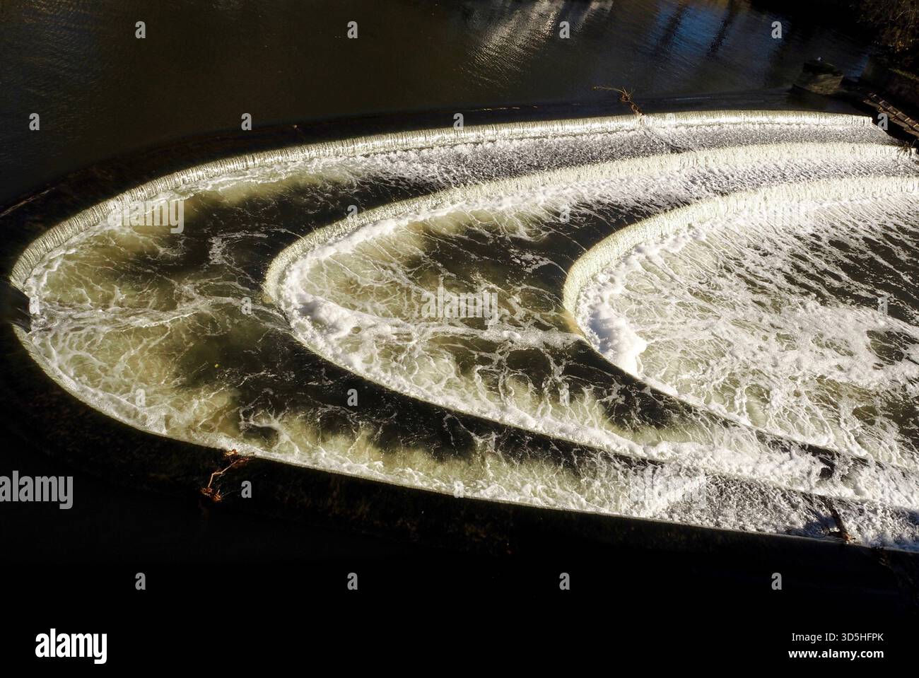 Acqua bianca che si tuffa sui tre livelli a ferro di cavallo di Pulteney Weir, sul fiume Avon, Bath Foto Stock