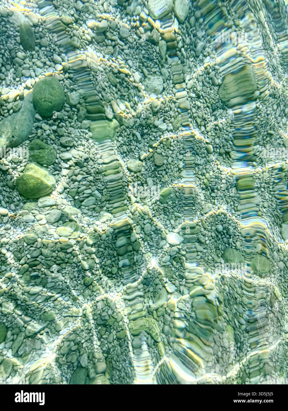 Acqua limpida che crea motivi di luce sui ciottoli sott'acqua nella baia di Sugiton, marsiglia Foto Stock