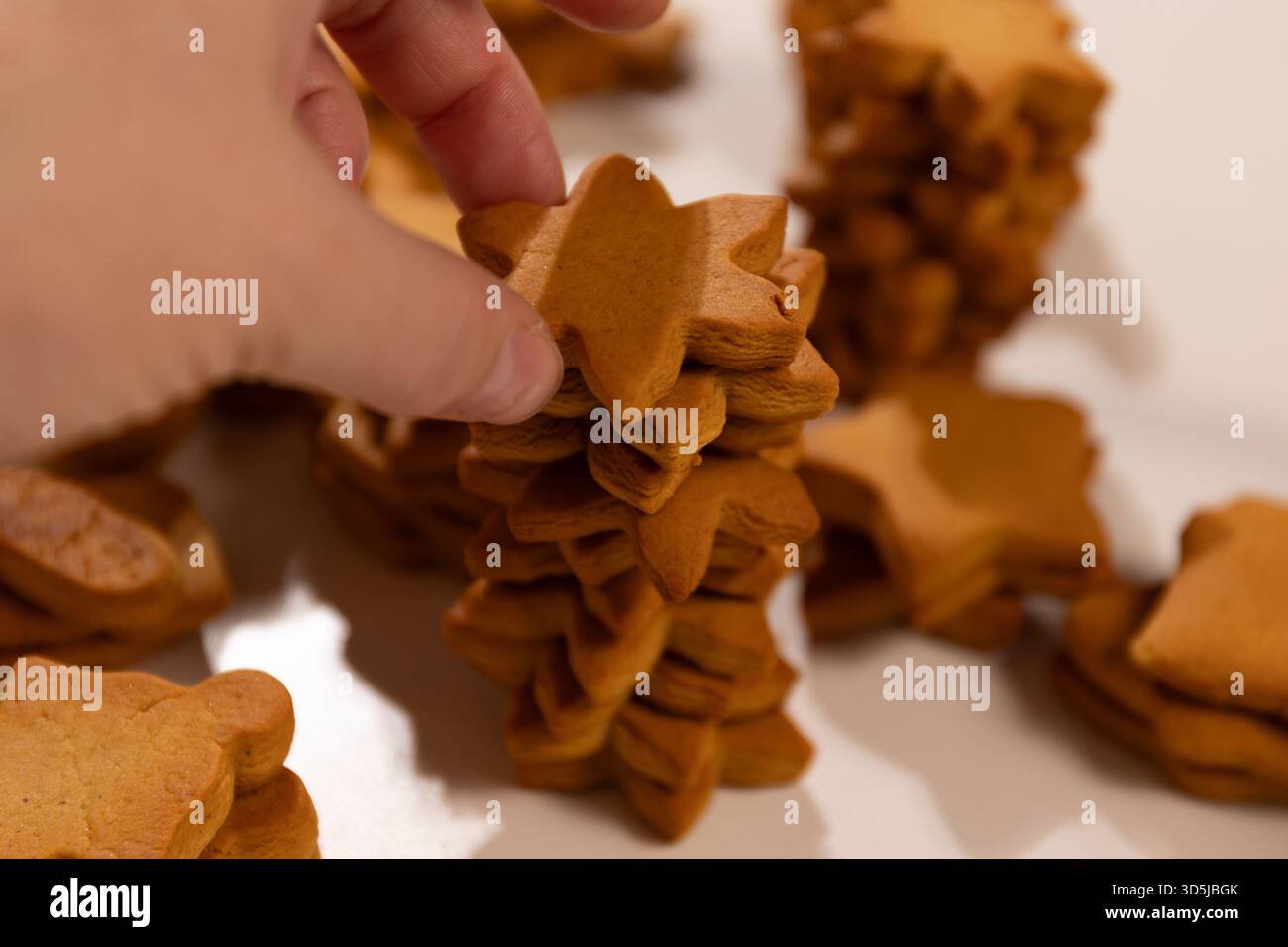 Una persona impila biscotti di pan di zenzero a forma di stella l'uno sull'altro. E' una festa di Natale. Preparatevi per la cottura delle vacanze. Foto Stock