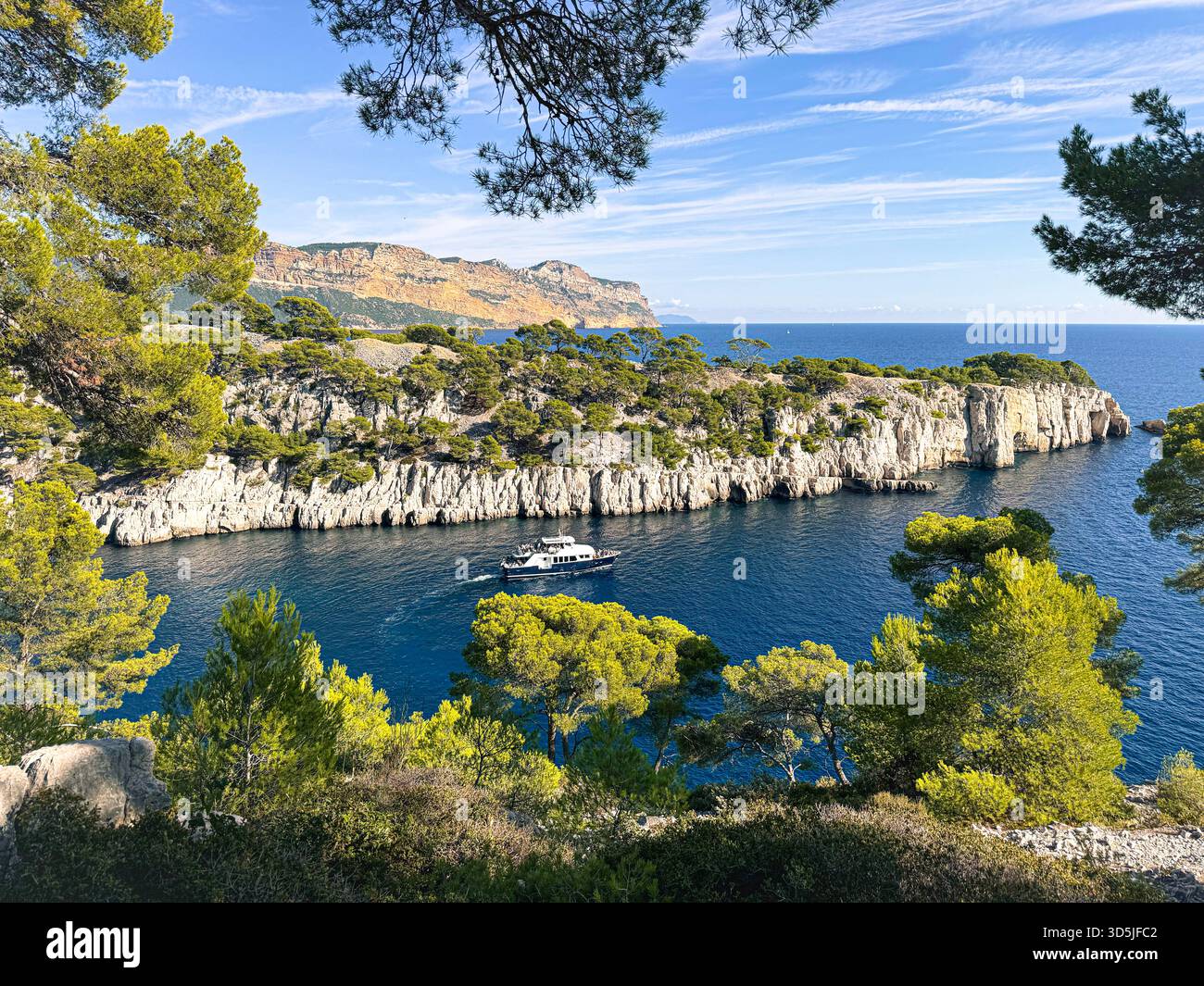 Calanque d'en vau mostra acqua blu, scogliere bianche e una barca che naviga nella baia panoramica Foto Stock
