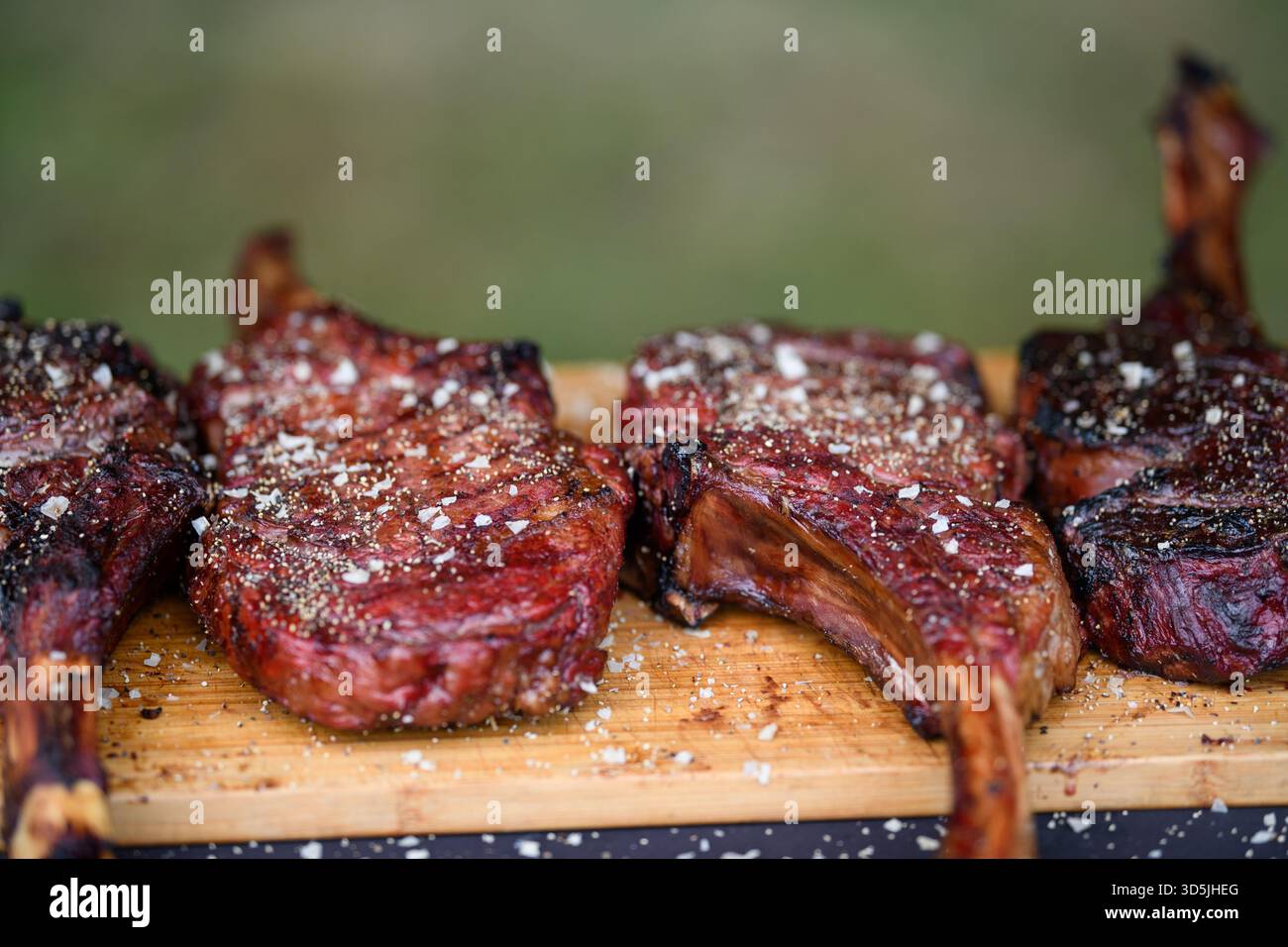 Primo piano di quattro bistecche Tomahawk su un tagliere di legno Foto Stock