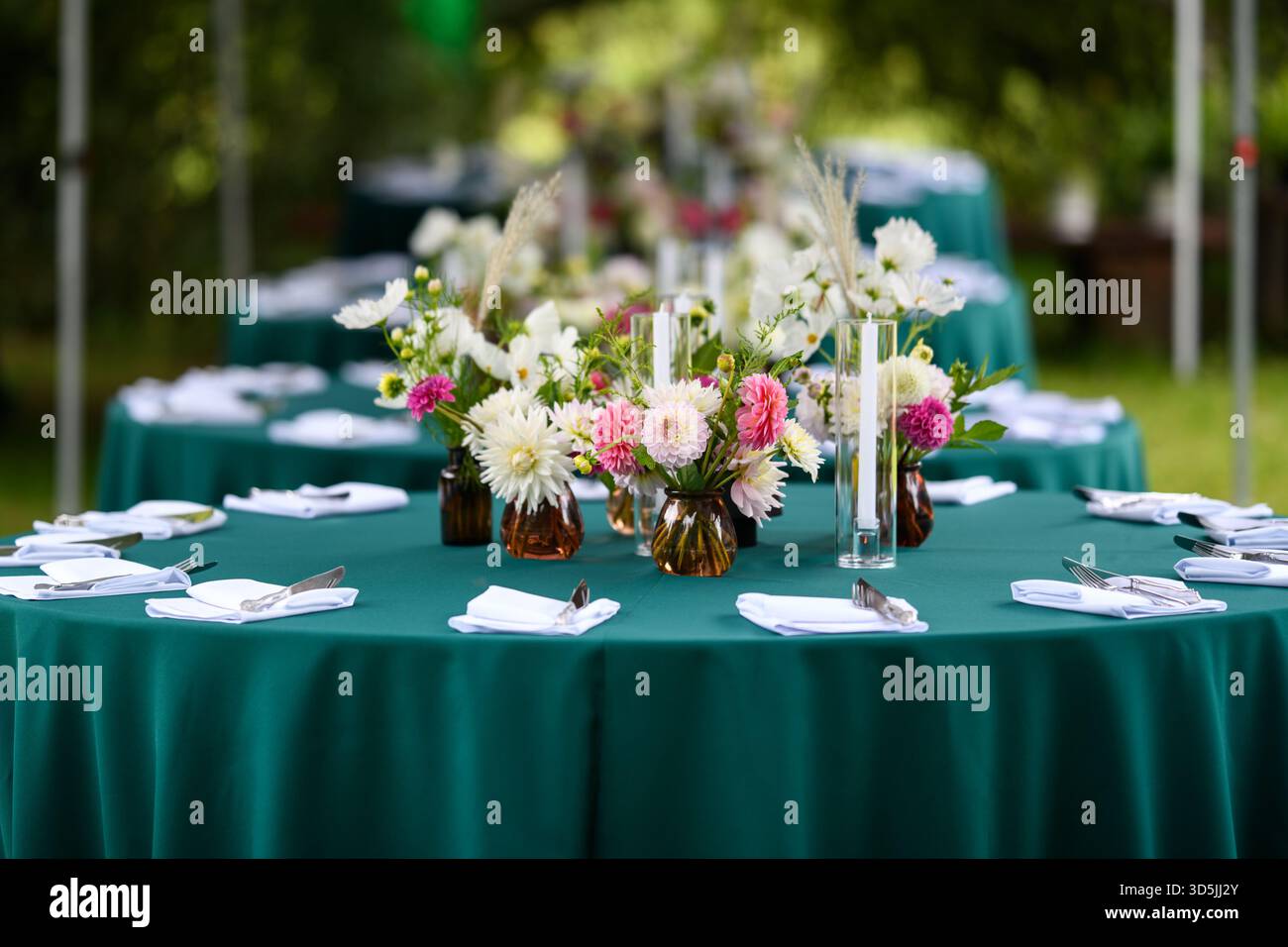 Tavoli eleganti con composizioni floreali assortite pronti per una festa in giardino Foto Stock