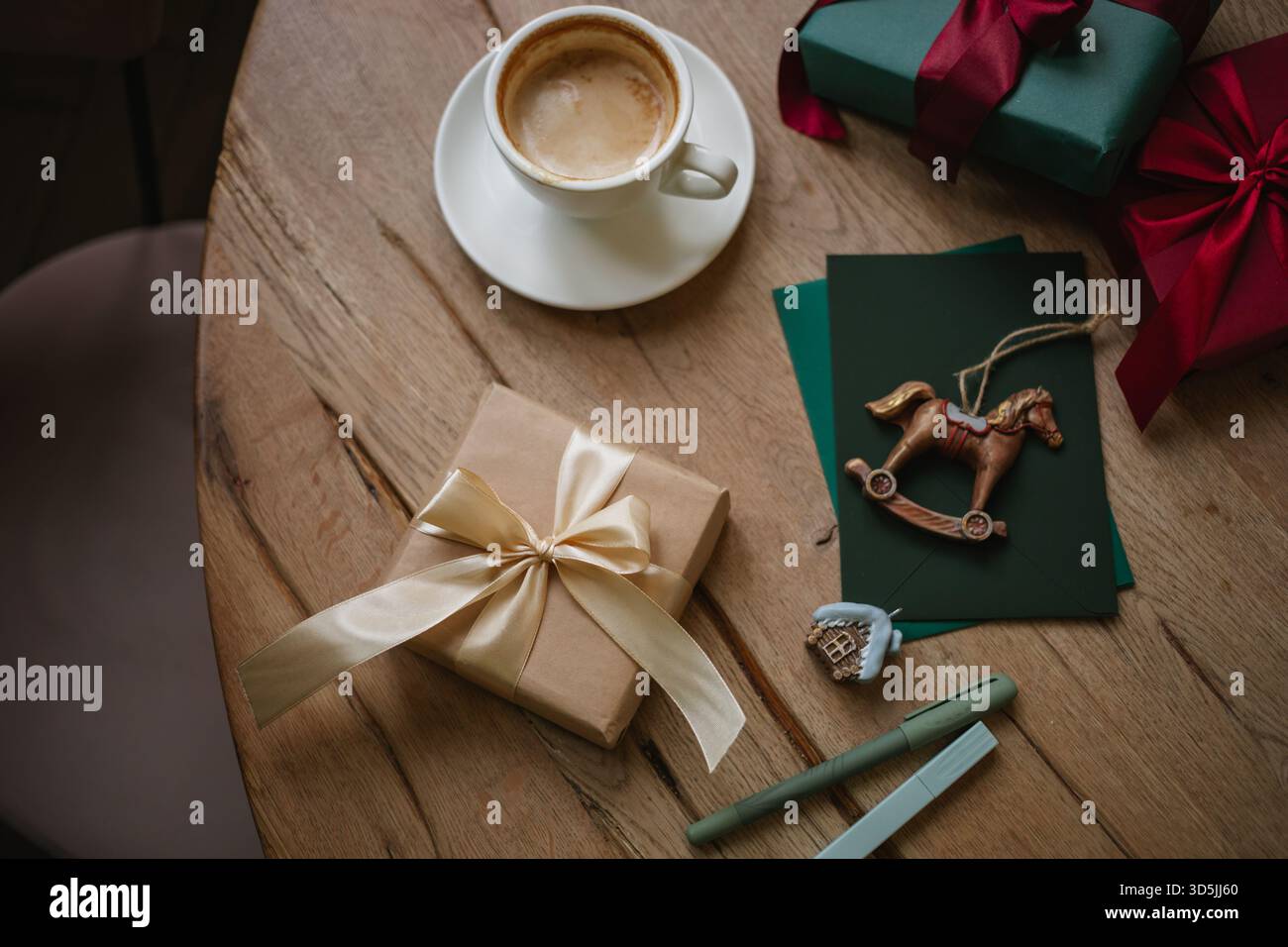 Vista dall'alto di un cappuccino su un tavolo con regali di Natale avvolti e decorazioni natalizie assortite Foto Stock