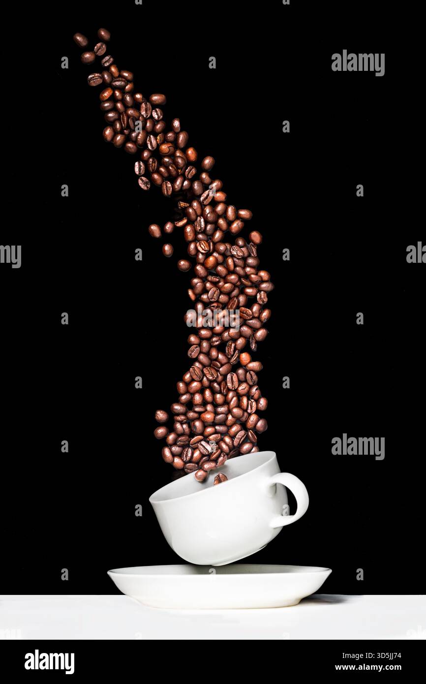 I chicchi di caffè cadono in una tazza Foto Stock