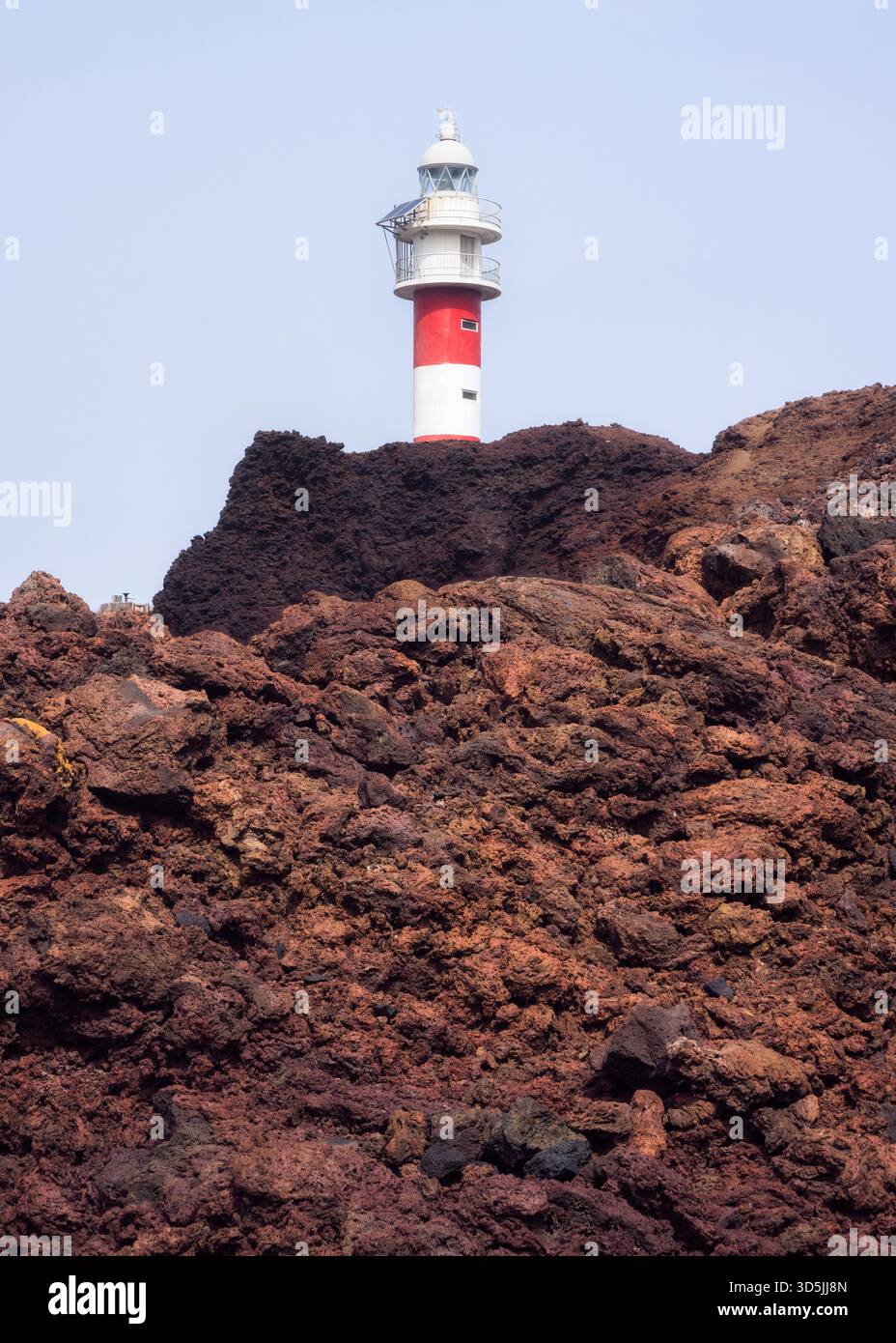 Il faro di Punta de Teno si erge alto contro scure rocce vulcaniche, guidando le navi vicino alla costa frastagliata di Tenerife. Foto Stock