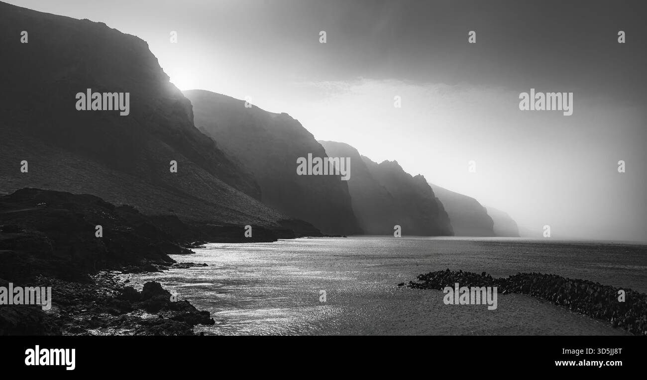 Le maestose scogliere sovrastano l'oceano, creando una splendida scena in bianco e nero a Los Gigantes, Tenerife. Foto Stock