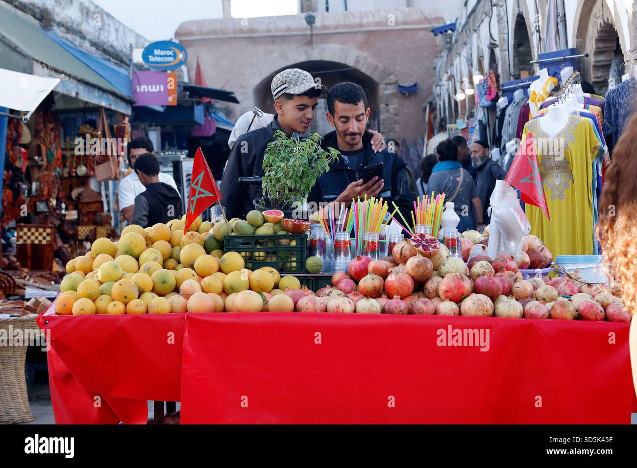 Un venditore di succhi con un amico guarda il suo smartphone a Essaouira, in Marocco Foto Stock