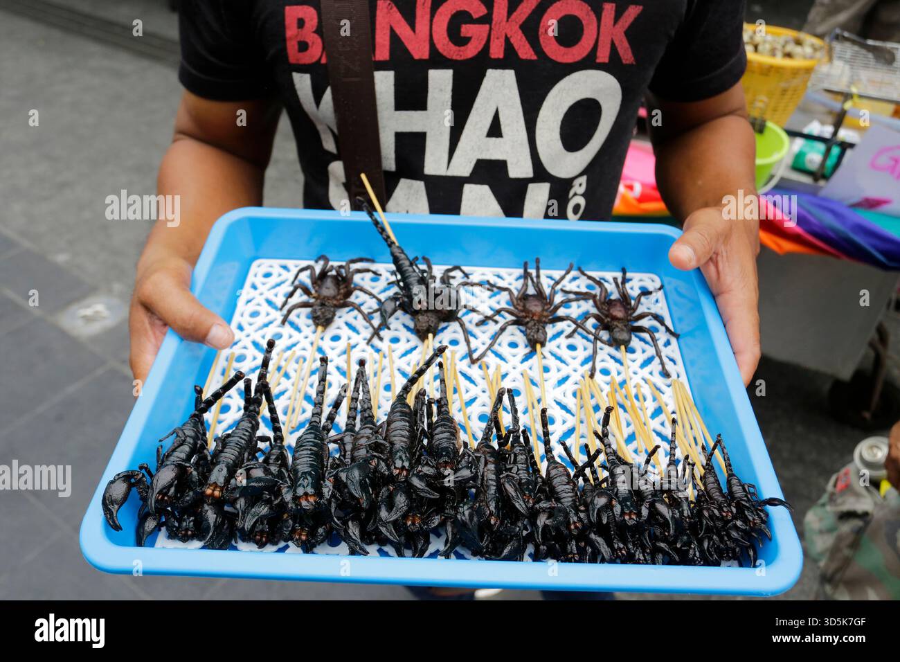 Bangkok, Thailandia - 22 luglio 2022: L'uomo vende scorpioni e ragni come cibi esotici nell'iconica via Khaosan Road. Foto Stock