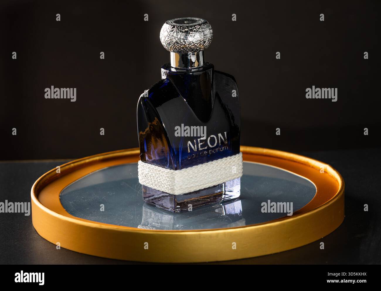Bottiglia di profumo di alta qualità su piattaforma esagonale luminosa con dettagli al neon arancione, liquido ambrato, illuminazione spettacolare e un'atmosfera futuristica di lusso. Foto Stock