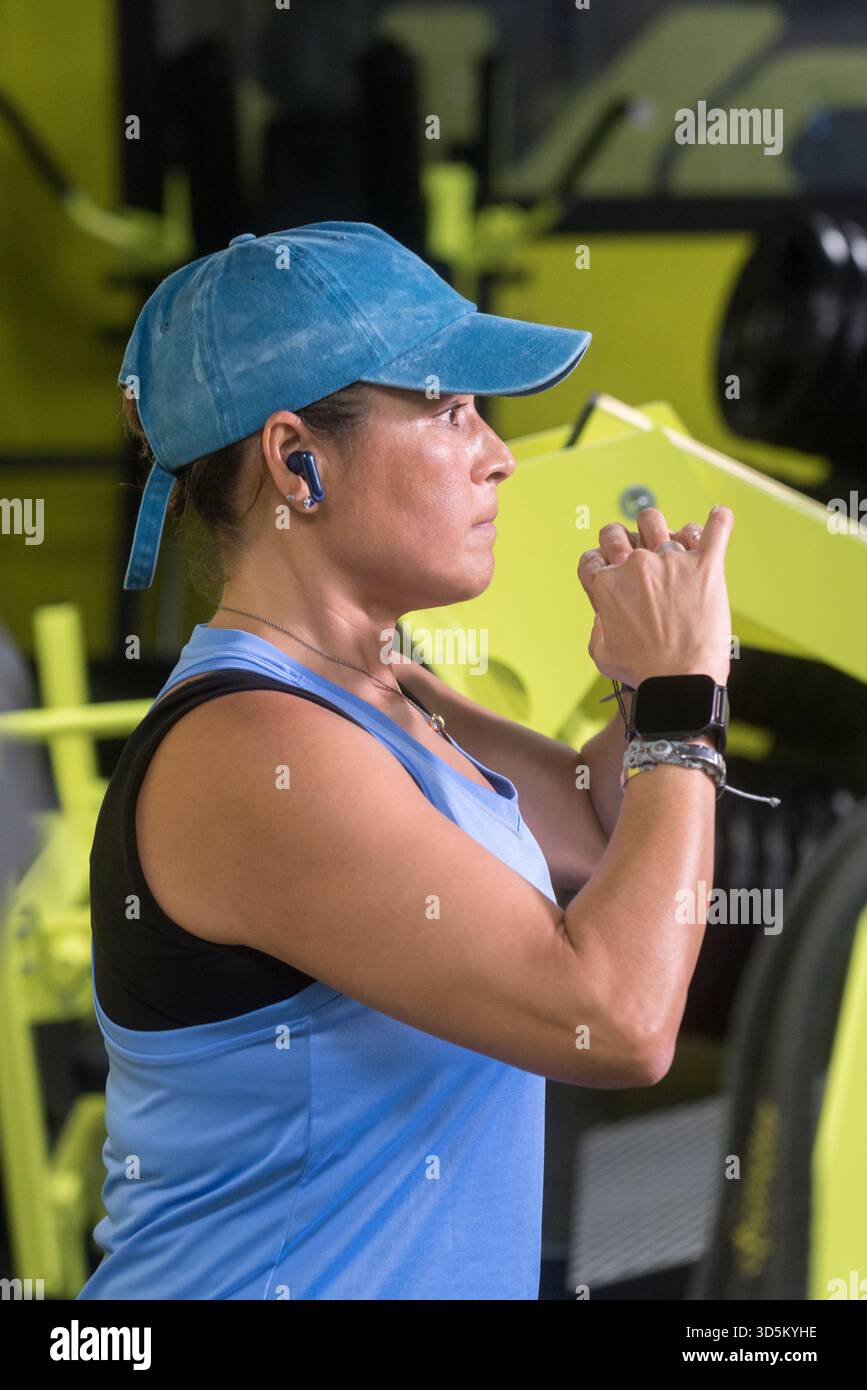Una donna di mezza età che fa gli squat, indossa un berretto e un abbigliamento sportivo blu. Foto Stock