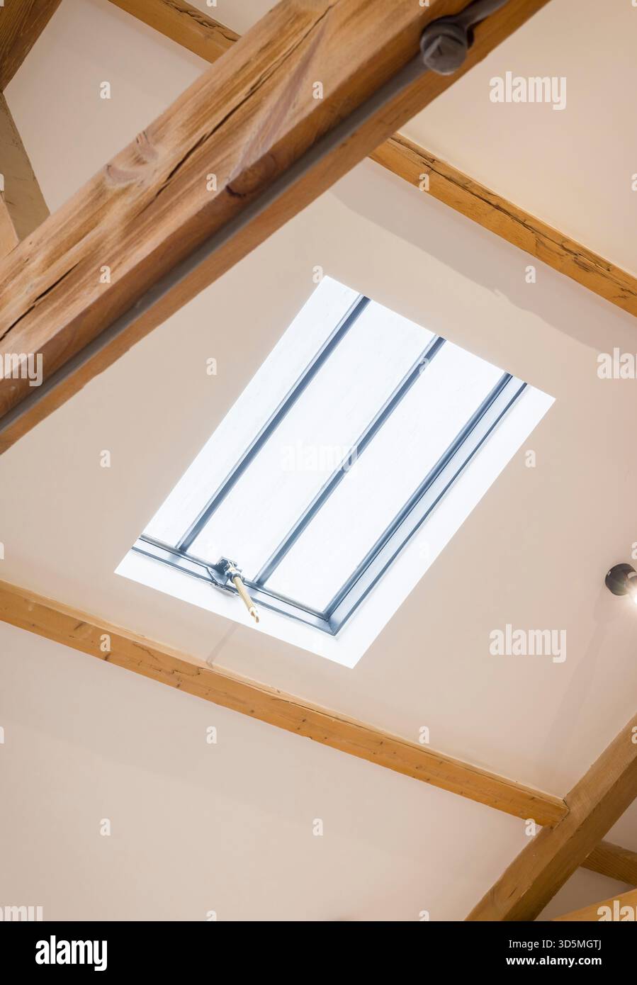 Lucernario sul tetto con soffitto inclinato bianco e travi di quercia esposte in una storica casa del Regno Unito, creando un luminoso spazio loft Foto Stock