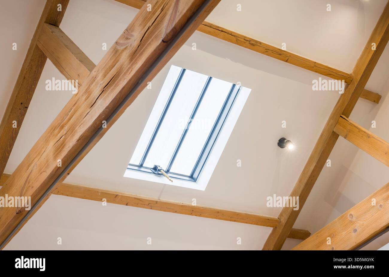 Lucernario sul tetto con soffitto inclinato bianco e travi di quercia esposte in una storica casa del Regno Unito, creando un luminoso spazio loft Foto Stock