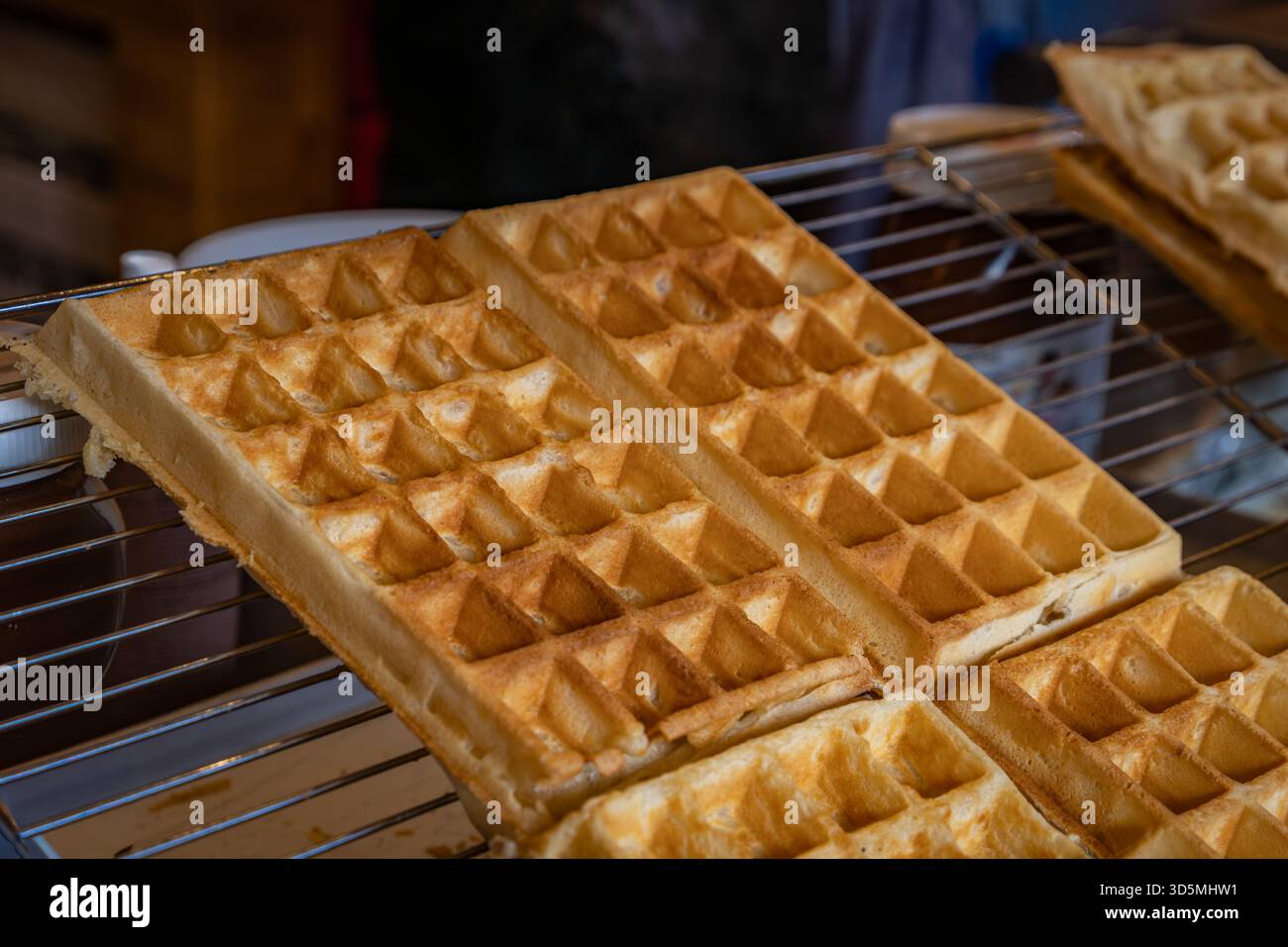 Il venditore cucina mini frittelle dorate in una speciale teglia sfrigolante al mercatino di Natale di Zurigo, in Svizzera Foto Stock
