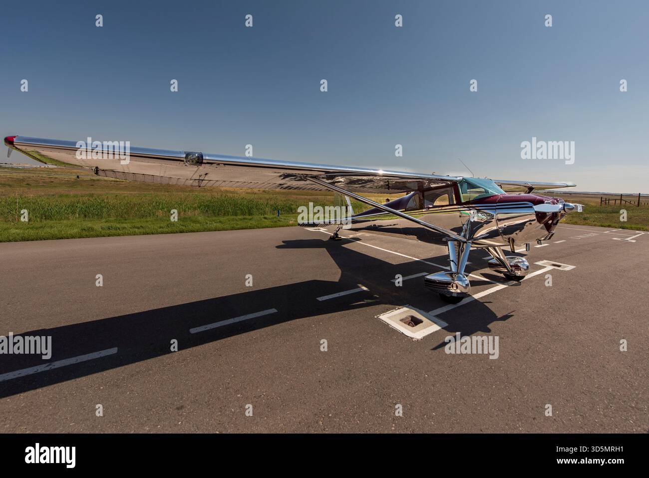 Aeroplano cromato d'epoca sulla pista sotto il cielo azzurro trasparente, icona Classic Travel and Aviation Foto Stock