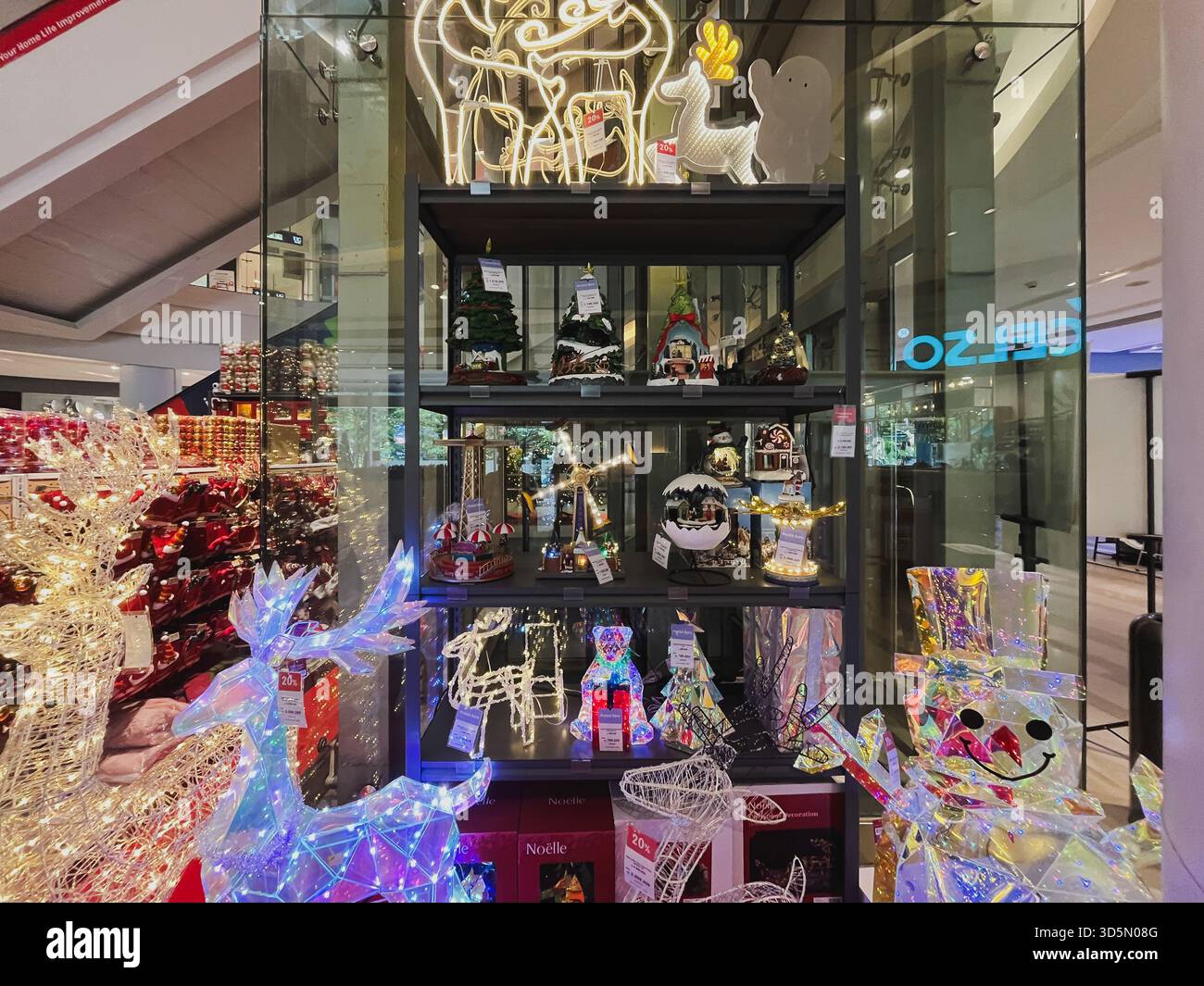 Balikpapan, Indonesia - 16 novembre 2025. Una vetrina di case in miniatura del villaggio natalizio, statue di renne illuminate e vari arredi per le vacanze Foto Stock