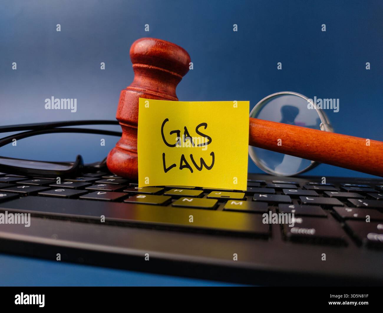Martelletto di legno, tastiera e appiccicoso con la parola LEGGE DEL GAS su sfondo blu. Foto Stock