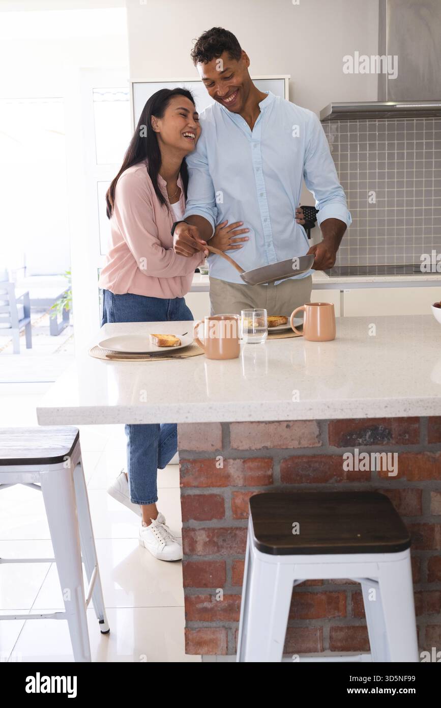 Abbinate la colazione cucinando insieme in una cucina moderna, condividendo momenti di gioia Foto Stock