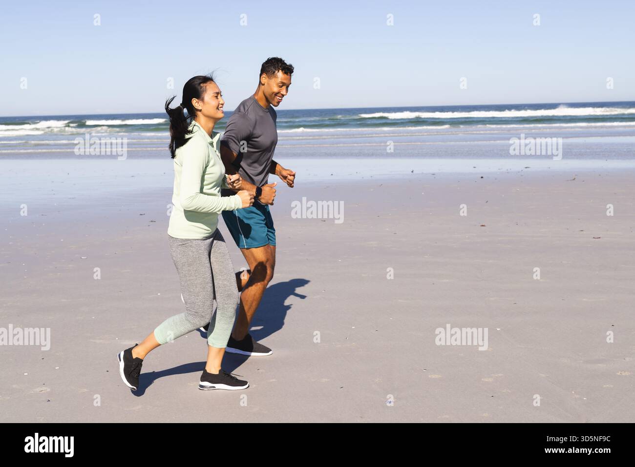 Coppia che fa jogging sulla spiaggia, si gode una giornata di sole e si mantiene attivi insieme, copia spazio Foto Stock