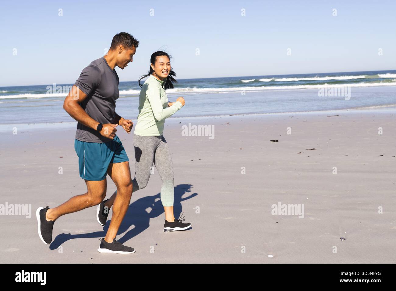 Coppie che fanno jogging sulla spiaggia, si godono gli esercizi mattutini e la fresca brezza dell'oceano, spazio per fotocopie Foto Stock